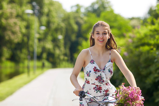 happy woman riding fixie bicycle in summer park - Zdjęcie, obraz