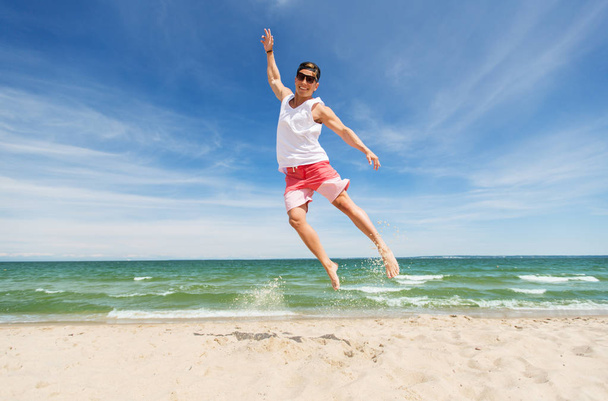 yaz plaj üzerinde atlama gülümseyen genç adam - Fotoğraf, Görsel