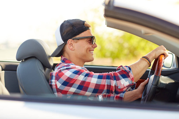 happy young man in shades driving convertible car - Фото, изображение