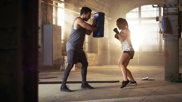 Athletic Woman Hits Punching Bag that Her Partner/ Trainer Holds - Fotografie, Obrázek