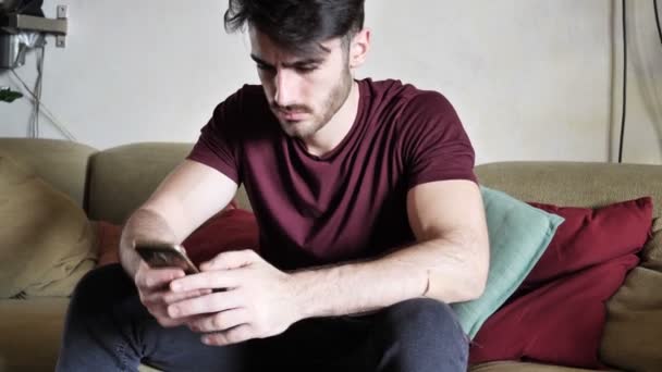 Attractive young man shopping online on mobile phone - Footage, Video