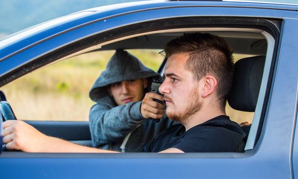 Un ladro, un criminale con una minaccia di pistola, cerca di rubare un'auto.
,  - Foto, immagini
