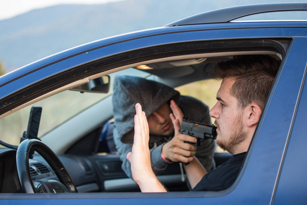 Un voleur, un criminel avec une menace de pistolet, tente de voler une voiture
,  - Photo, image