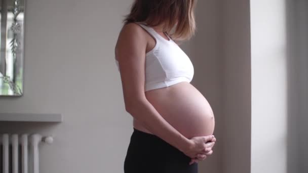 Pregnant woman with hands on bare stomach - Video