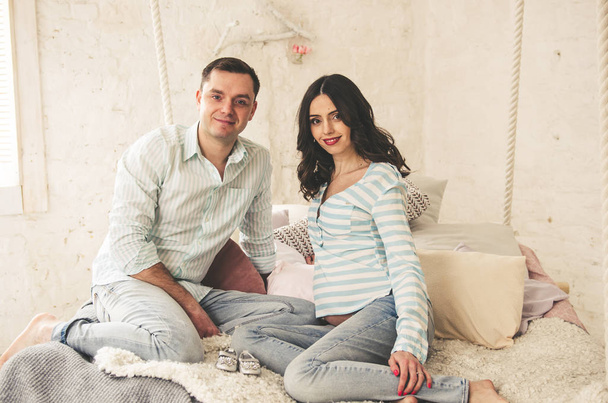 Beautiful happy couple of pregnant woman and young man posing on camera - Фото, зображення