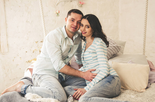 Beautiful happy couple of pregnant woman and young man posing on camera - Фото, зображення