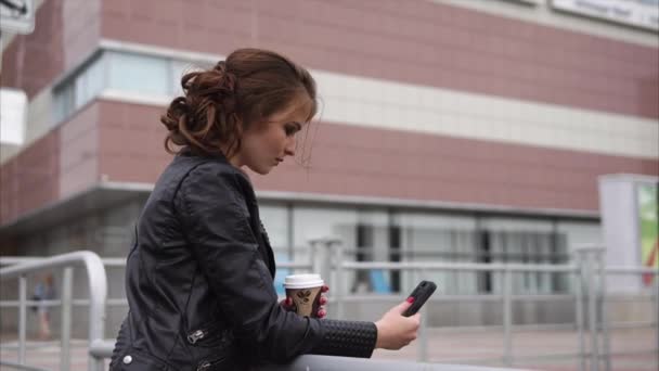 hübsche Brünette mit Handy und Kaffee auf der Straße - Filmmaterial, Video