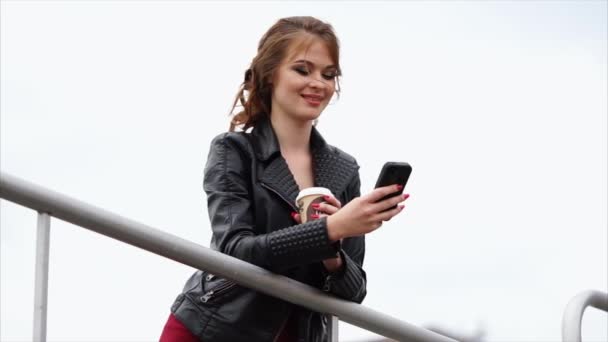 Νεαρή γυναίκα με το καφέ και το κινητό τηλέφωνο εξωτερική στην πόλη - Πλάνα, βίντεο