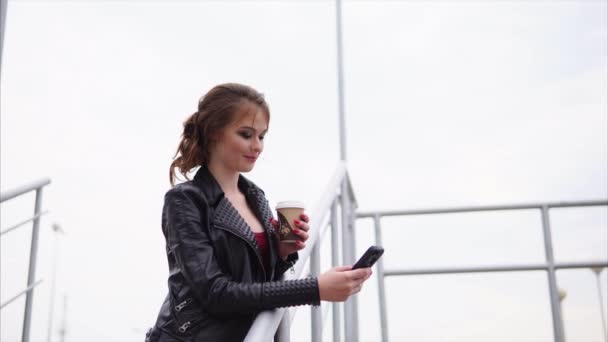hübsche Brünette mit Handy und Kaffee auf der Straße - Filmmaterial, Video