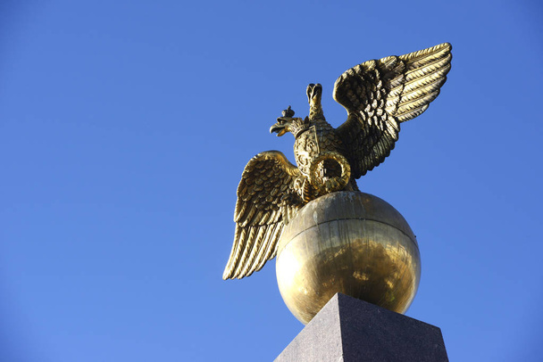 Obelisco de águia dourada de duas cabeças na praça do mercado em Helsinque
 - Foto, Imagem