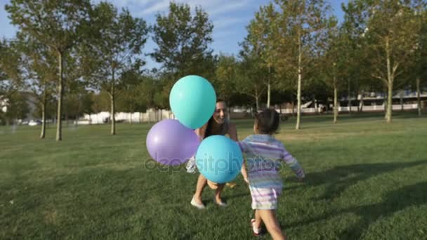 Little girl running in park to her mother and she embracing with daughter - Imágenes, Vídeo