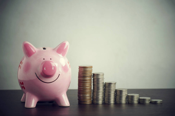 pilha de moedas de dinheiro com o banco piggy rosa na mesa de madeira
 - Foto, Imagem