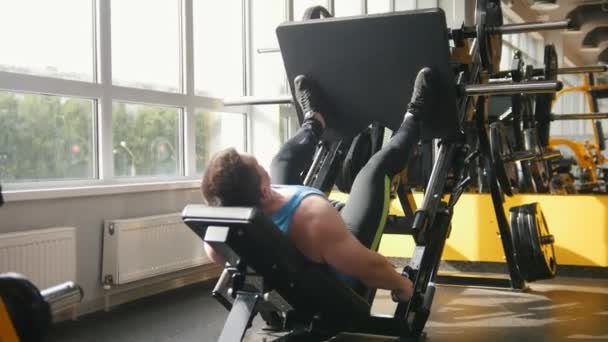 Fitness club - muscular man exercising on leg press machine - Footage, Video