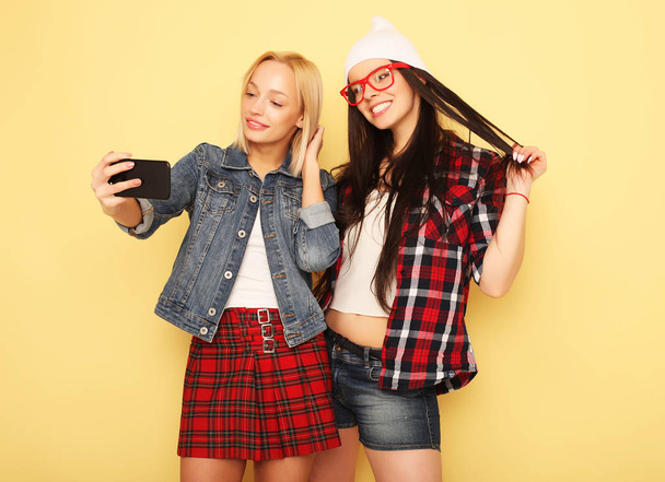 Happy girls  with smartphone  over yellow background. Happy self - Photo, image