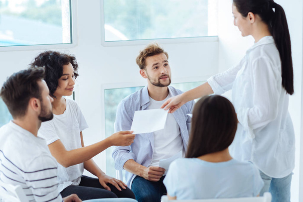 Professional group therapist giving sheets of paper - Photo, Image