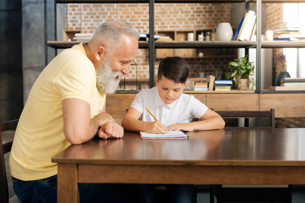Loving grandfather watching his grandson do sums - Photo, image