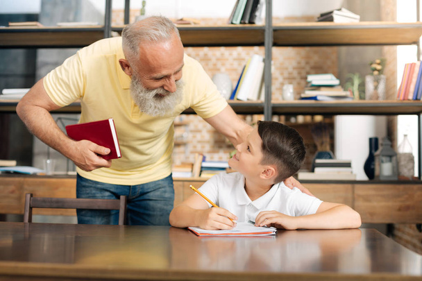 Caring grandfather checking his grandsons progress in homework - Photo, image