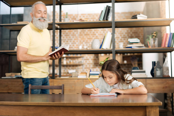 Joyful grandfather dictating words to his granddaughter - Photo, image