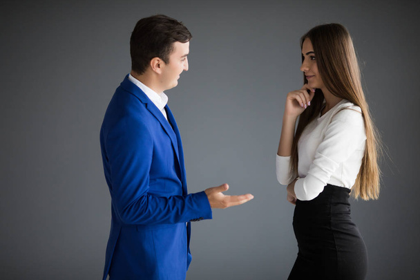Serios businesswoman and businessman are conversing against grey background. - Foto, immagini