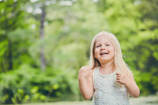 Portrait of laughing little girl in white dress - Valokuva, kuva