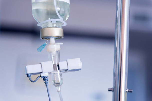 Detailní záběr odkapávací solný roztok pro pacienta a infuzní pumpy v nemocnici, léčbu nemoci doktor koncepce. - Fotografie, Obrázek