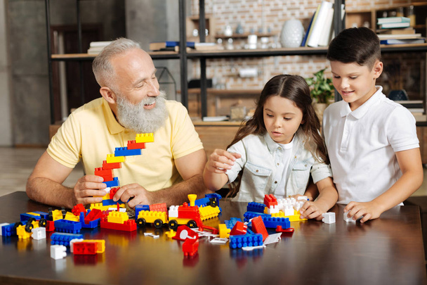 Grandfather and his grandchildren assembling a new construction set - Foto, afbeelding