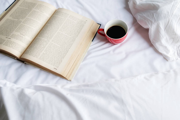 Piękna kobieta siedzi na łóżku i czytanie książek. Rano z książką. Koncepcja relaksujący. Efekt retro filtra, nieostrość, Selektywny fokus. - Zdjęcie, obraz