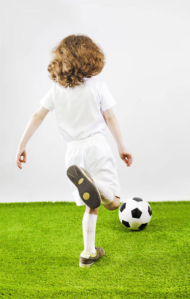 Boy with soccer ball on a gray background. Back view - Foto, imagen