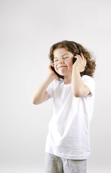 Music and technology concept.Caucasian little boy with headphone on gray background - Photo, Image