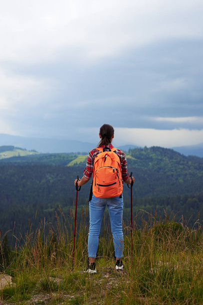 Mujer de pie con bastones de senderismo en la cima de la montaña
 - Foto, Imagen