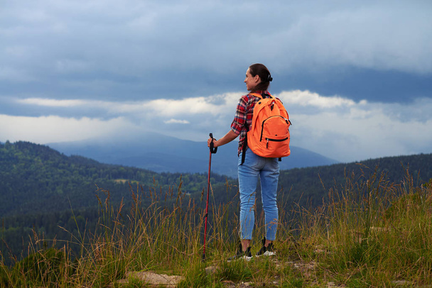 Hymyilevä nainen seisoo vuorella katsoo vasemmalle
  - Valokuva, kuva