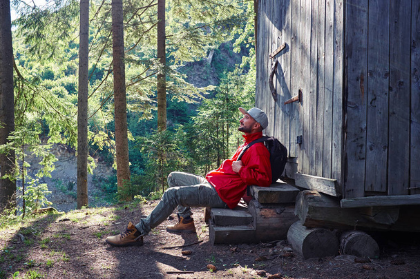 Inspirierter Mann sitzt auf Treppe eines Holzhauses  - Foto, Bild