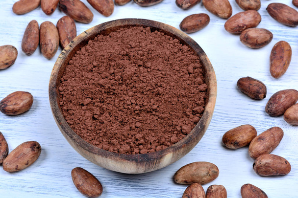 Kakaopulver in einer Schüssel mit Bohnen auf Holztisch - Foto, Bild