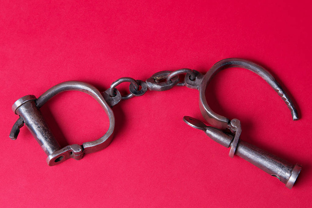 Vintage handcuffs on a scarlet background. - Foto, imagen