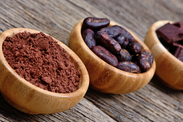 Какао порошок бобы и темный шоколад в мисках
 - Фото, изображение
