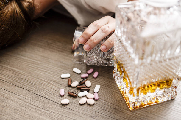 drunk or poisoned young woman with bottle of alcohol and pills - Photo, Image
