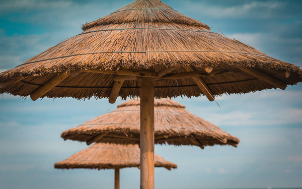 Tres sombrillas de playa de paja en el cielo azul
 - Foto, imagen