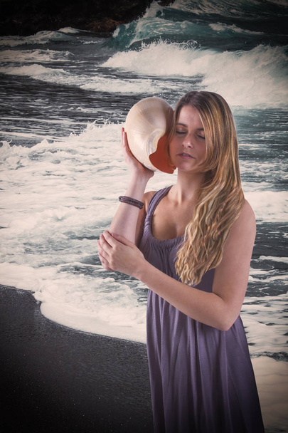Романтична молода жінка з великою черепашкою на березі моря
. - Фото, зображення