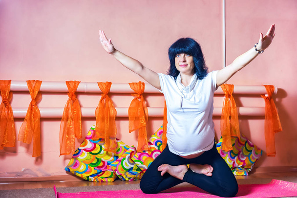 40 semaines enceinte femme caucasienne d'âge moyen debout sur les genoux avec ses jambes croix dans le lotus et tenir les bras en l'asana faire de l'exercice de yoga
.  - Photo, image