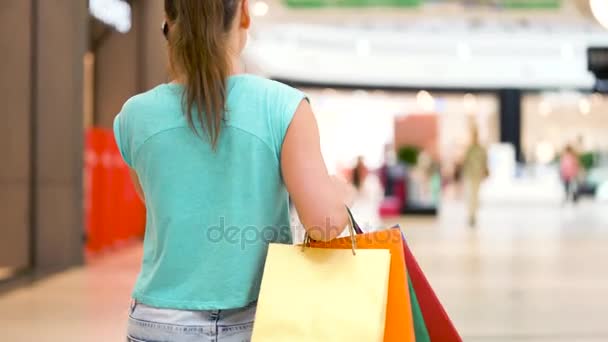 Bir alışveriş merkezinde bir smartphone cep telefonu ile konuşurken kağıt poşet olan kadın - Video, Çekim