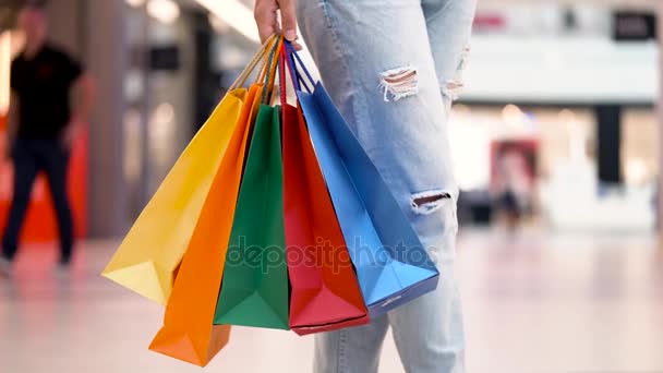 Vrouw met veelkleurige papieren zakken loopt rond het winkelcentrum - Video