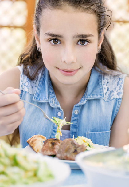 Krásná usměvavá holčička s radostí jí kebab venkovní - Fotografie, Obrázek