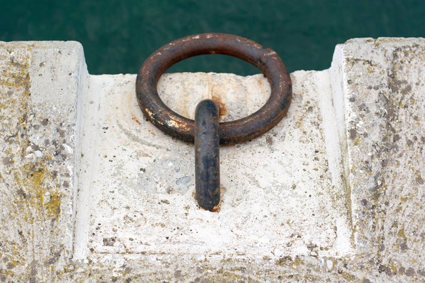 Dock Cleats em um cais para amarrar barcos com mar verde como a parte de trás
 - Foto, Imagem