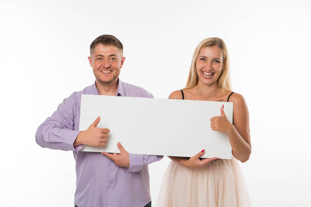 Young happy couple showing presentation pointing placard. - Fotó, kép