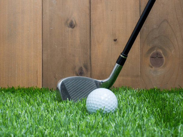 Golf en bal op het groene gras en houten achtergrond - Foto, afbeelding