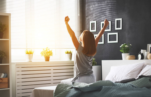 junge Frau wachte morgens im Schlafzimmer am Wind auf - Foto, Bild