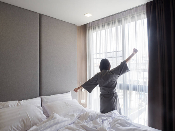Woman stretching in bed after waking up, back view - Foto, Imagen