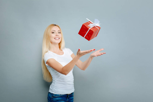 Happy blonde throwing gift box up - Foto, afbeelding