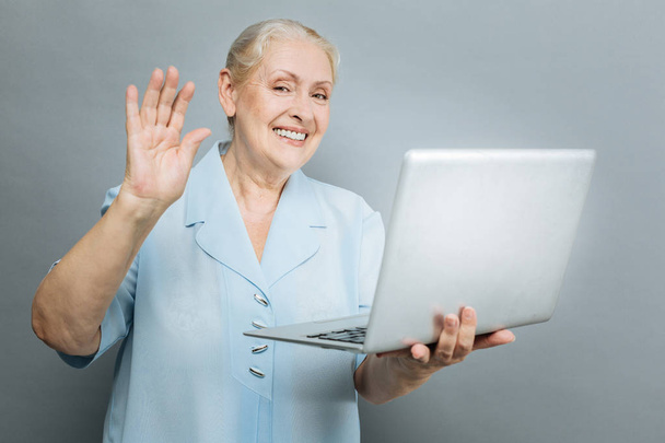 Positive mature female waving her right hand - Foto, immagini
