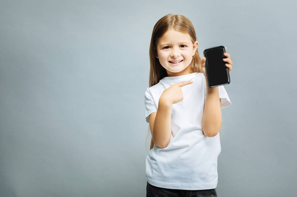 Cheerful kid pointing at her telephone - Фото, изображение